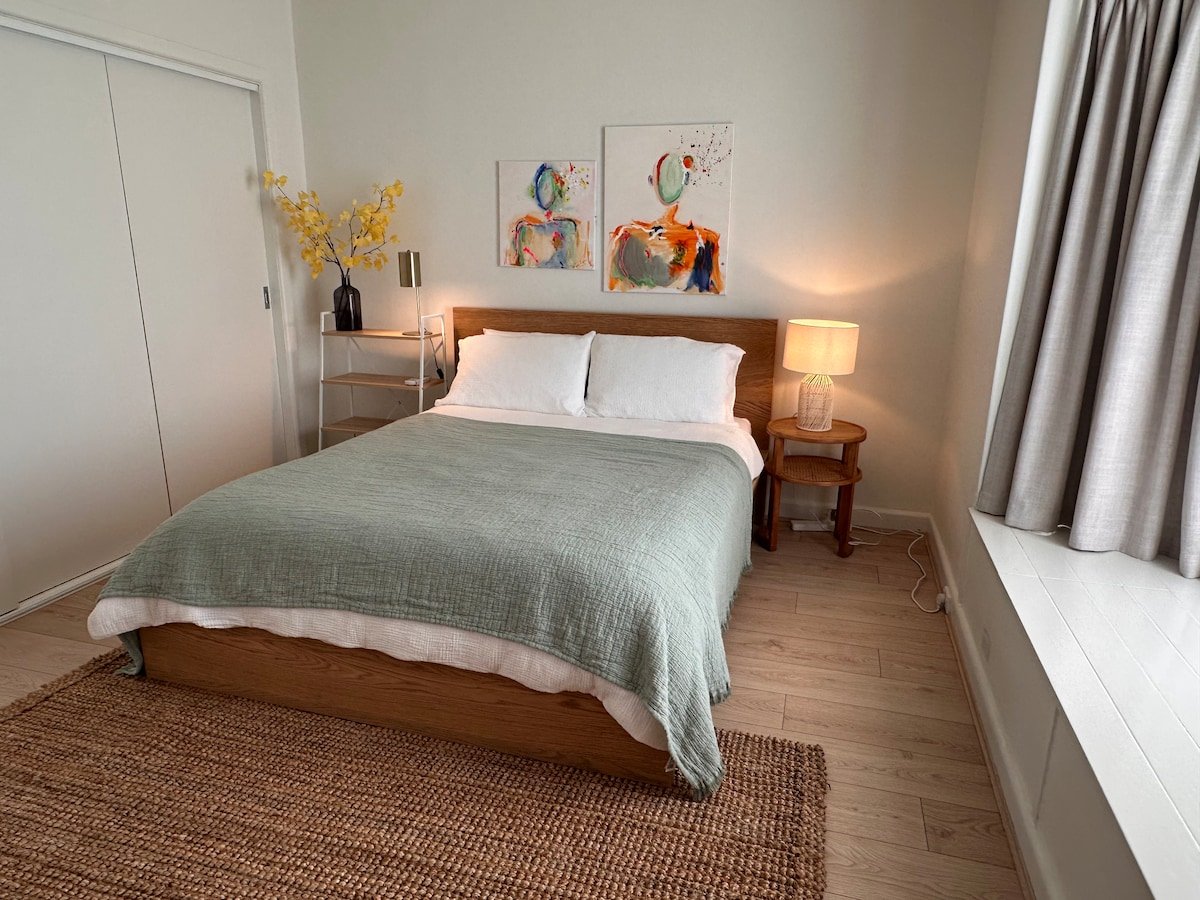 Queen bedroom with soft lighting and blackout curtains